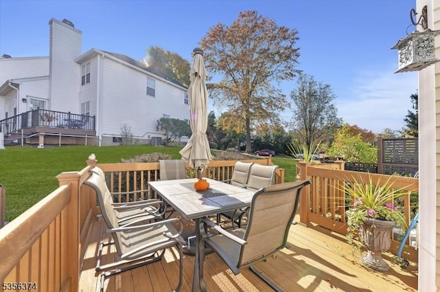 wooden terrace with outdoor dining area and a lawn
