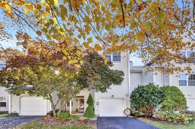 obstructed view of property featuring asphalt driveway and a garage