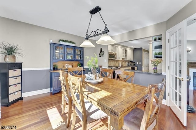 dining space featuring light wood-type flooring, baseboards, and french doors