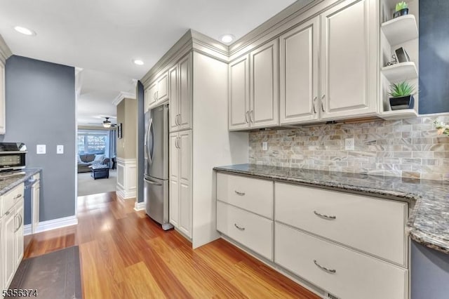 kitchen with freestanding refrigerator, a ceiling fan, tasteful backsplash, light wood finished floors, and crown molding