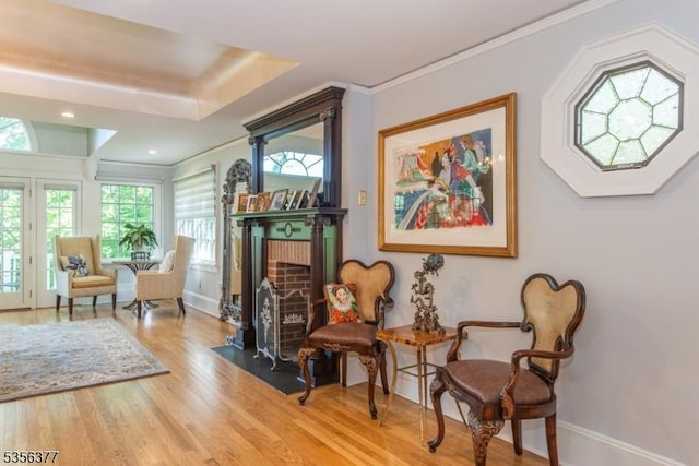 sitting room featuring a fireplace with flush hearth, wood finished floors, baseboards, crown molding, and recessed lighting