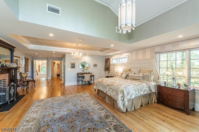 bedroom with a chandelier, wood finished floors, a raised ceiling, crown molding, and recessed lighting