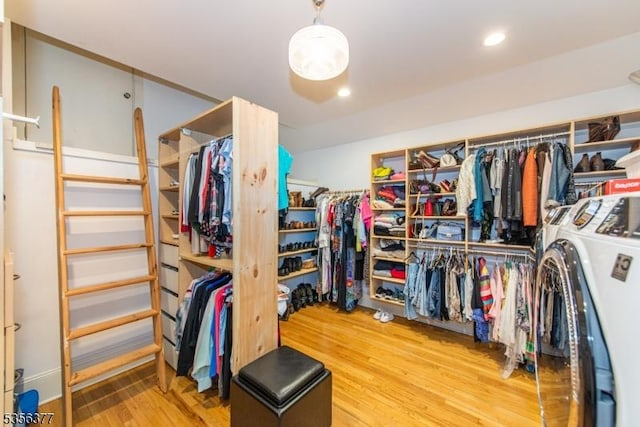 walk in closet with wood finished floors and separate washer and dryer