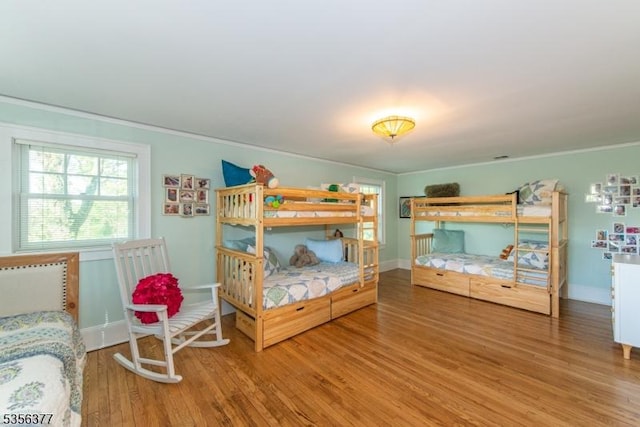 bedroom with wood finished floors, ornamental molding, and baseboards