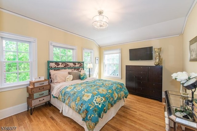bedroom featuring multiple windows, ornamental molding, wood finished floors, baseboards, and a chandelier