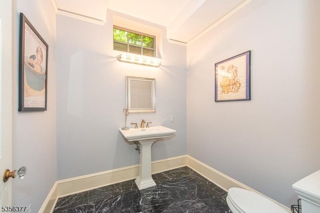 half bathroom with marble look tiles, baseboards, and toilet