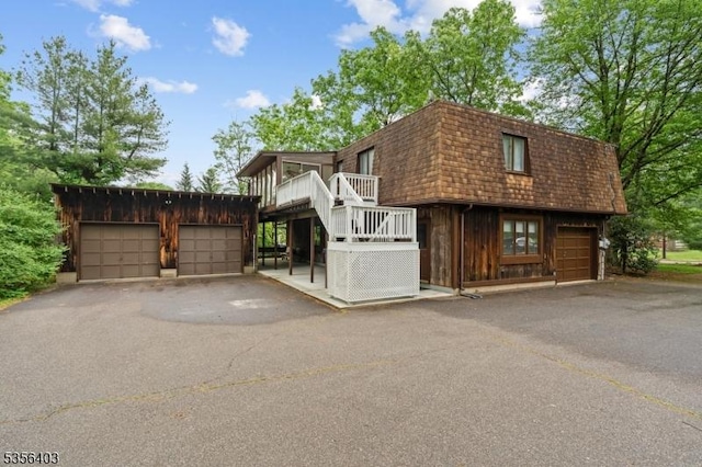 87 Ivy Ln, Bridgewater Twp, NJ 08807 - view of front of home featuring mansard roof, an outdoor structure, a wooden deck, and a garage
