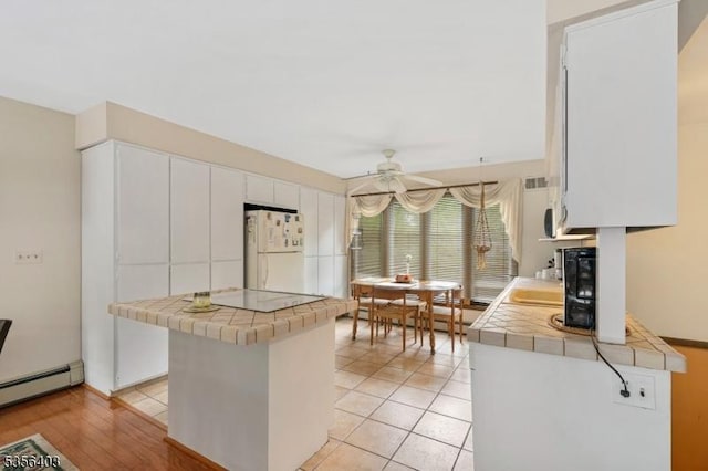 87 Ivy Ln, Bridgewater Twp, NJ 08807 - kitchen with freestanding refrigerator, tile counters, ceiling fan, a baseboard heating unit, and white cabinets