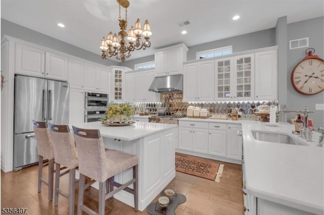 16 Gordon Way, Mount Olive Twp, NJ 07836 - kitchen with stainless steel appliances, under cabinet range hood, a breakfast bar, tasteful backsplash, and a chandelier