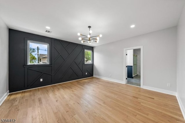 empty room with a chandelier, baseboards, light wood-type flooring, and recessed lighting