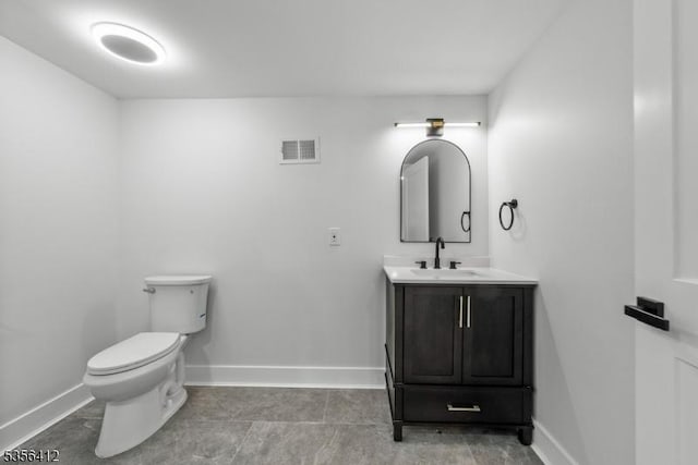 half bath featuring baseboards, toilet, vanity, and tile patterned flooring