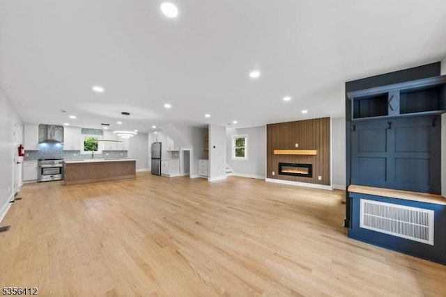 unfurnished living room featuring recessed lighting, baseboards, a fireplace, and light wood-type flooring