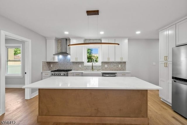kitchen with wall chimney exhaust hood, stainless steel appliances, a sink, backsplash, and recessed lighting