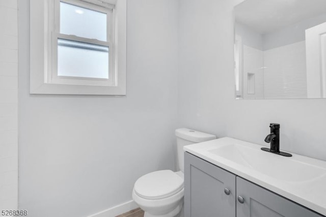full bathroom featuring toilet, vanity, a shower, and baseboards