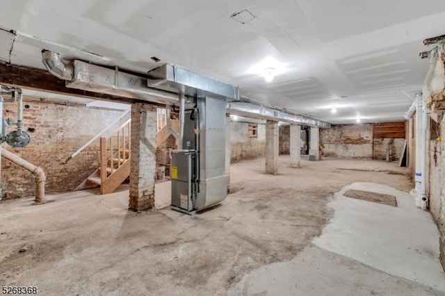 unfinished below grade area featuring heating unit and stairs
