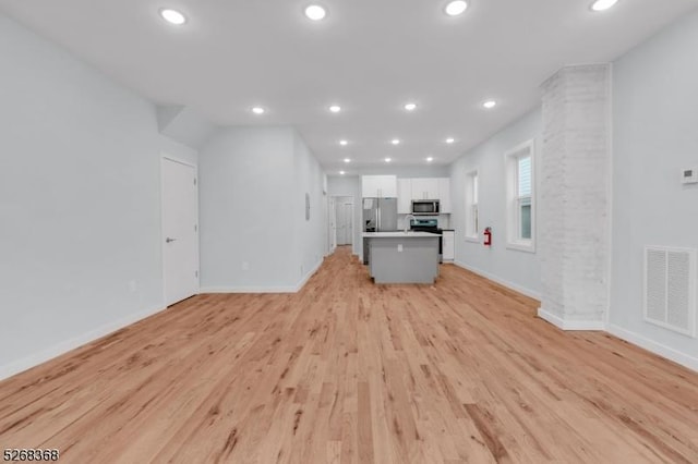unfurnished living room featuring recessed lighting, baseboards, and light wood-type flooring