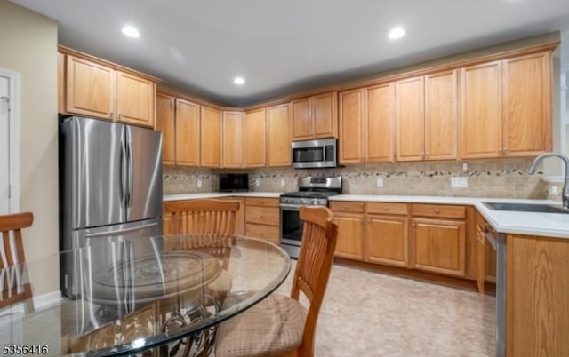 kitchen with stainless steel appliances, a sink, tasteful backsplash, recessed lighting, and light countertops