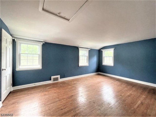 unfurnished room featuring wood finished floors, baseboards, and lofted ceiling
