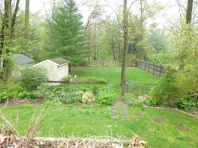 view of yard featuring a storage unit, an outdoor structure, and a forest view