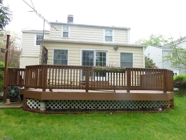 rear view of house featuring a lawn, a chimney, and a wooden deck