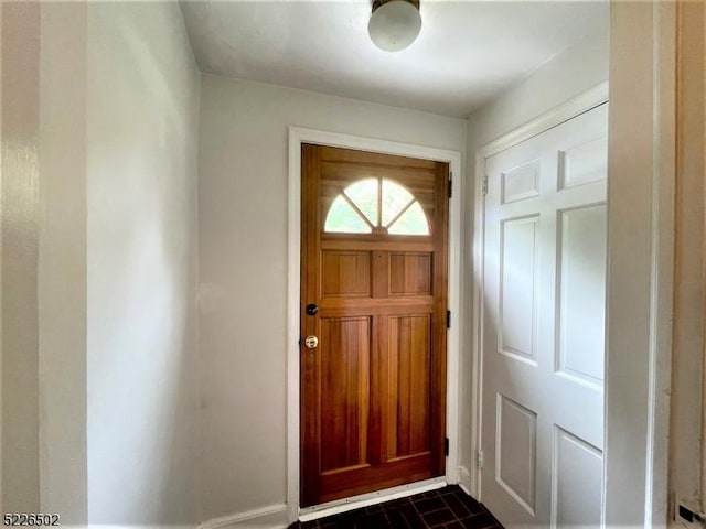 doorway to outside featuring brick patterned floors and baseboards