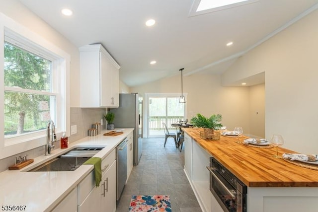 kitchen featuring wood counters, a sink, stainless steel appliances, recessed lighting, and white cabinetry