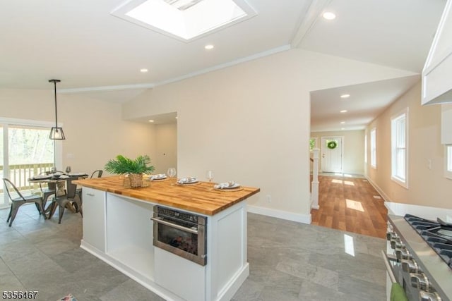 kitchen featuring butcher block counters, lofted ceiling, appliances with stainless steel finishes, healthy amount of natural light, and white cabinets