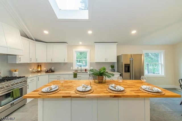 kitchen featuring appliances with stainless steel finishes, wooden counters, a sink, decorative backsplash, and white cabinets