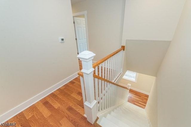 staircase featuring wood finished floors and baseboards