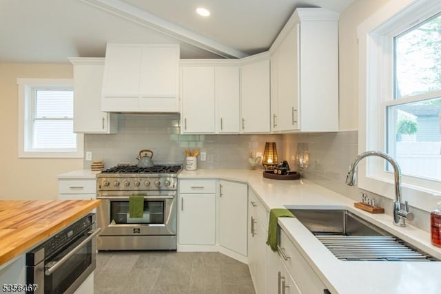 kitchen featuring stainless steel appliances, a sink, wooden counters, backsplash, and recessed lighting