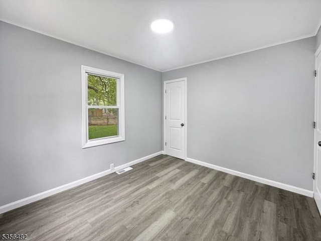 spare room featuring wood finished floors, baseboards, and ornamental molding