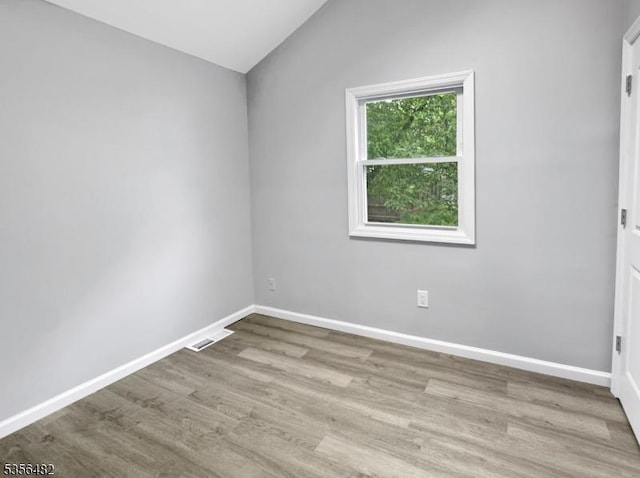 unfurnished room featuring vaulted ceiling, baseboards, and wood finished floors