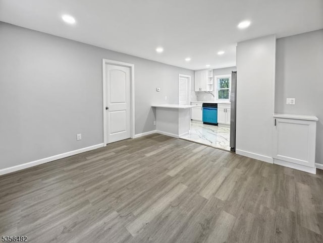 unfurnished living room featuring wood finished floors, recessed lighting, and baseboards