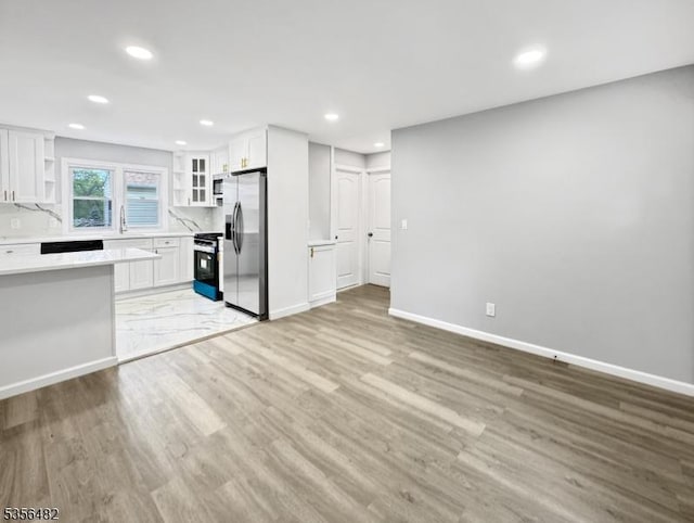 unfurnished living room with recessed lighting, light wood-style floors, baseboards, and a sink