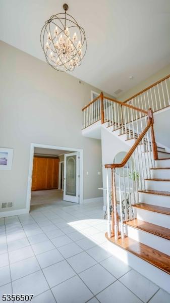 1 Dewing Ct, Raritan Twp, NJ 08551 - staircase featuring a towering ceiling, tile patterned flooring, a chandelier, and baseboards