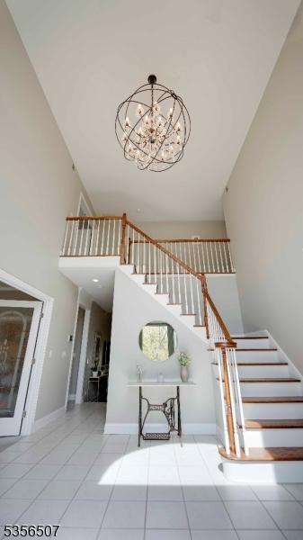 1 Dewing Ct, Raritan Twp, NJ 08551 - stairway featuring tile patterned floors, a towering ceiling, a chandelier, and baseboards