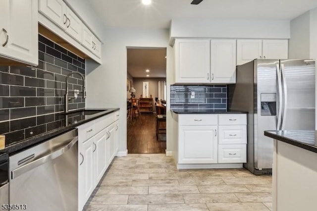 kitchen with stainless steel appliances, tasteful backsplash, white cabinetry, dark countertops, and recessed lighting