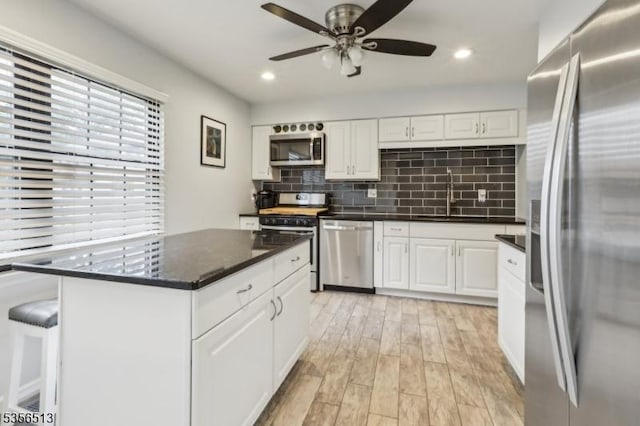 kitchen featuring stainless steel appliances, a sink, white cabinetry, backsplash, and recessed lighting
