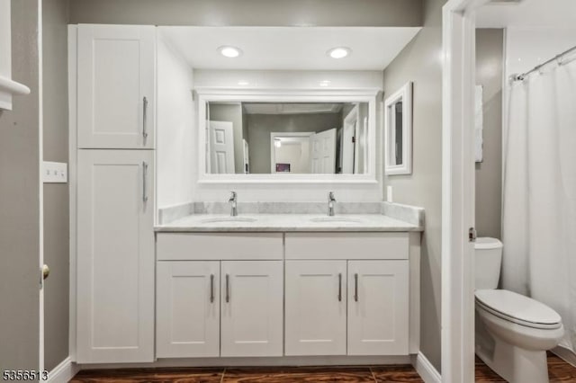 full bath featuring toilet, recessed lighting, double vanity, and baseboards