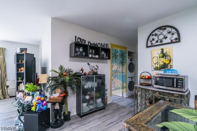 bar featuring stacked washing machine and dryer, stainless steel microwave, and wood finished floors