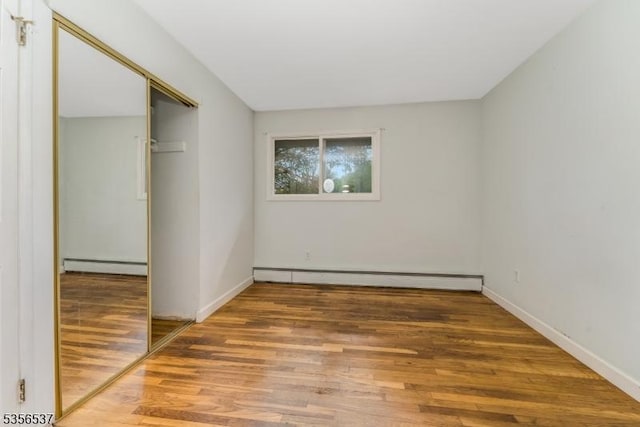 unfurnished room with a baseboard radiator, light wood-style floors, and baseboards