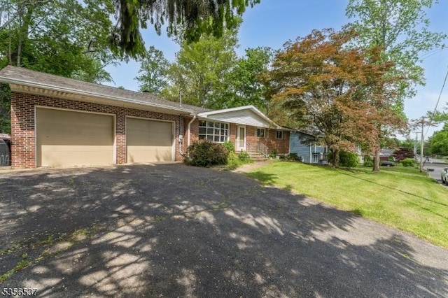 ranch-style home with brick siding, an attached garage, asphalt driveway, and a front lawn