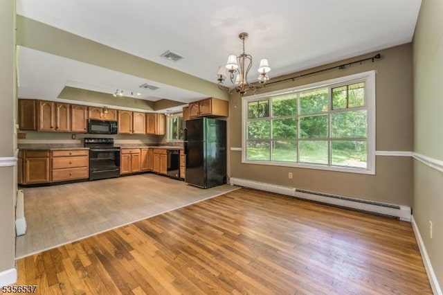 kitchen with black appliances, a chandelier, light wood finished floors, baseboard heating, and baseboards