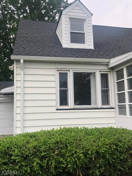 view of home's exterior with a shingled roof and a garage