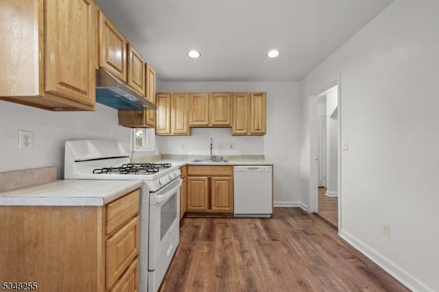 kitchen featuring white appliances, under cabinet range hood, a sink, dark wood-style floors, and recessed lighting