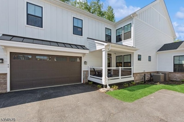 view of front of house featuring board and batten siding, a porch, driveway, and an attached garage