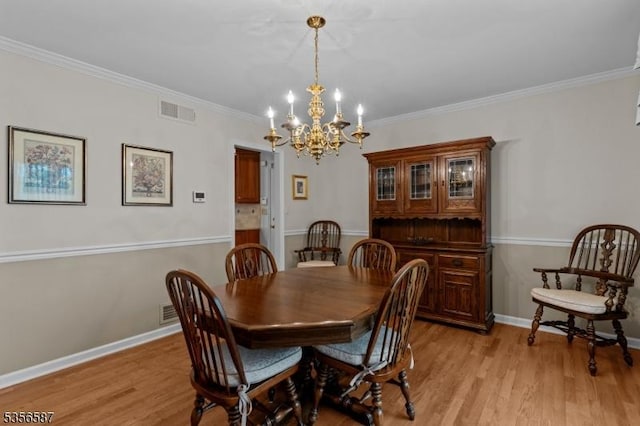 dining space featuring a chandelier, light wood finished floors, ornamental molding, and baseboards