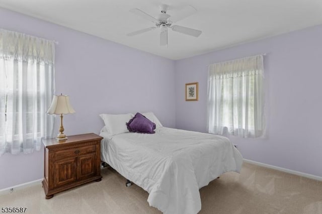bedroom featuring multiple windows, carpet flooring, baseboards, and a ceiling fan