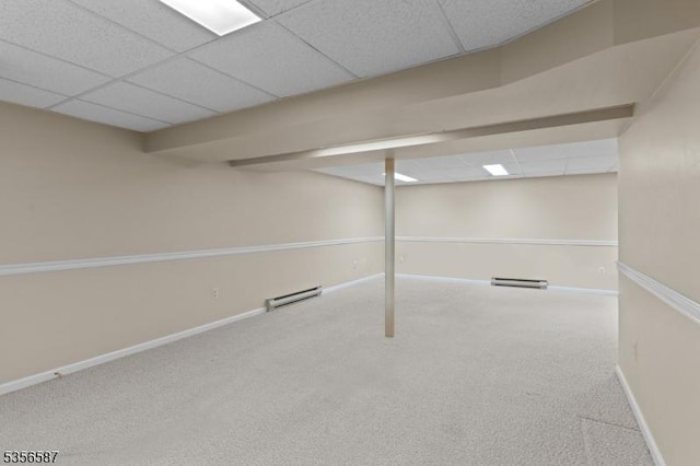 finished below grade area with baseboards, carpet floors, a drop ceiling, and baseboard heating
