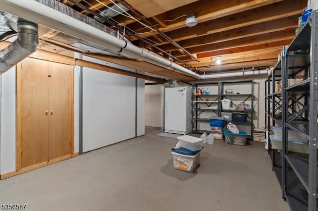 unfinished basement featuring freestanding refrigerator